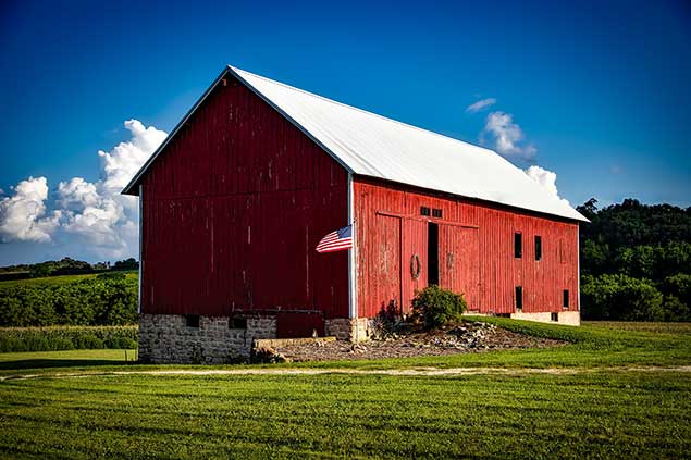 Red Barn surrounded by grass and trees in background