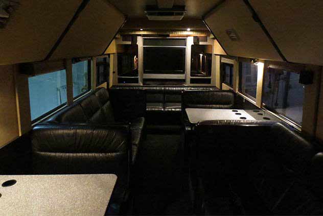 Interior of Windstar Charter bus with tv, leather chairs, and tables