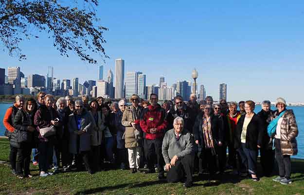 Group of Charter bus riders by river with city skyline in background