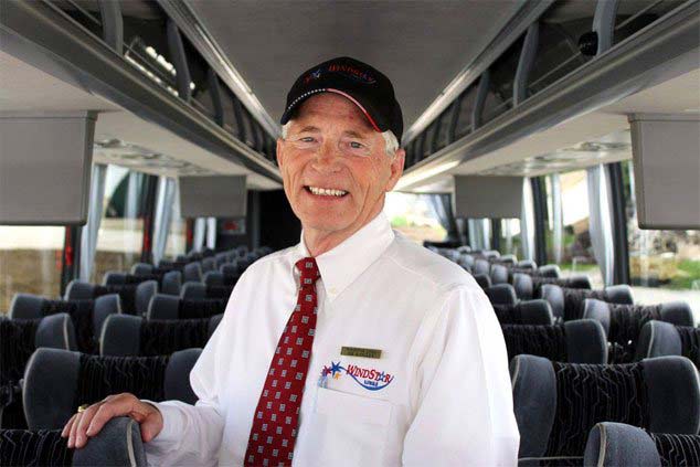Male Windstar Bus Driver smiling & standing in aisle of Windstar Bus