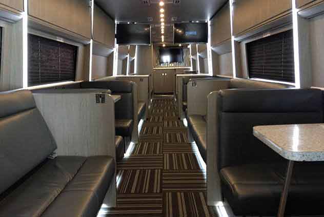 Interior of Windstar Charter Bus with Leather seats, two tv screens, and tables